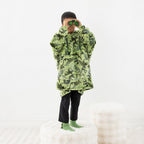 Child wearing a green dinosaur print hoodie while standing on a white stool.
