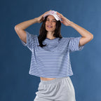 Woman wearing the Simple & Sunday Lounge Relaxed Stripe Tee in Faded Blue with grey lounge shorts and a pink cap.