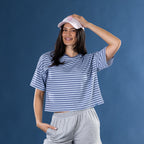 Woman wearing the Simple & Sunday Lounge Relaxed Stripe Tee in Faded Blue with grey lounge shorts and a pink cap.