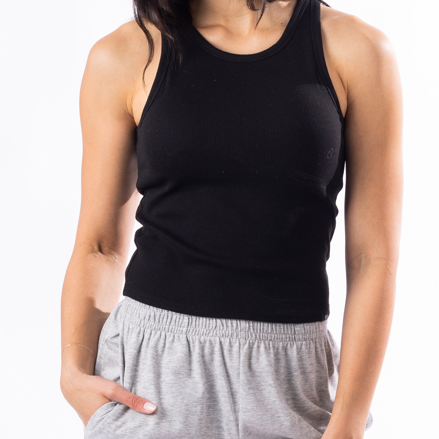 A woman wearing a black ribbed tank top and light gray heather sweatpants, cropped from the nose down against a plain white background.