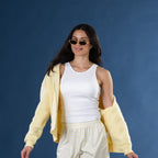 Model wearing the White Simple & Sunday Lounge Weekend Ribbed Tank Top with matching striped lounge shorts, a yellow zip hoodie and sunglasses against a blue background.