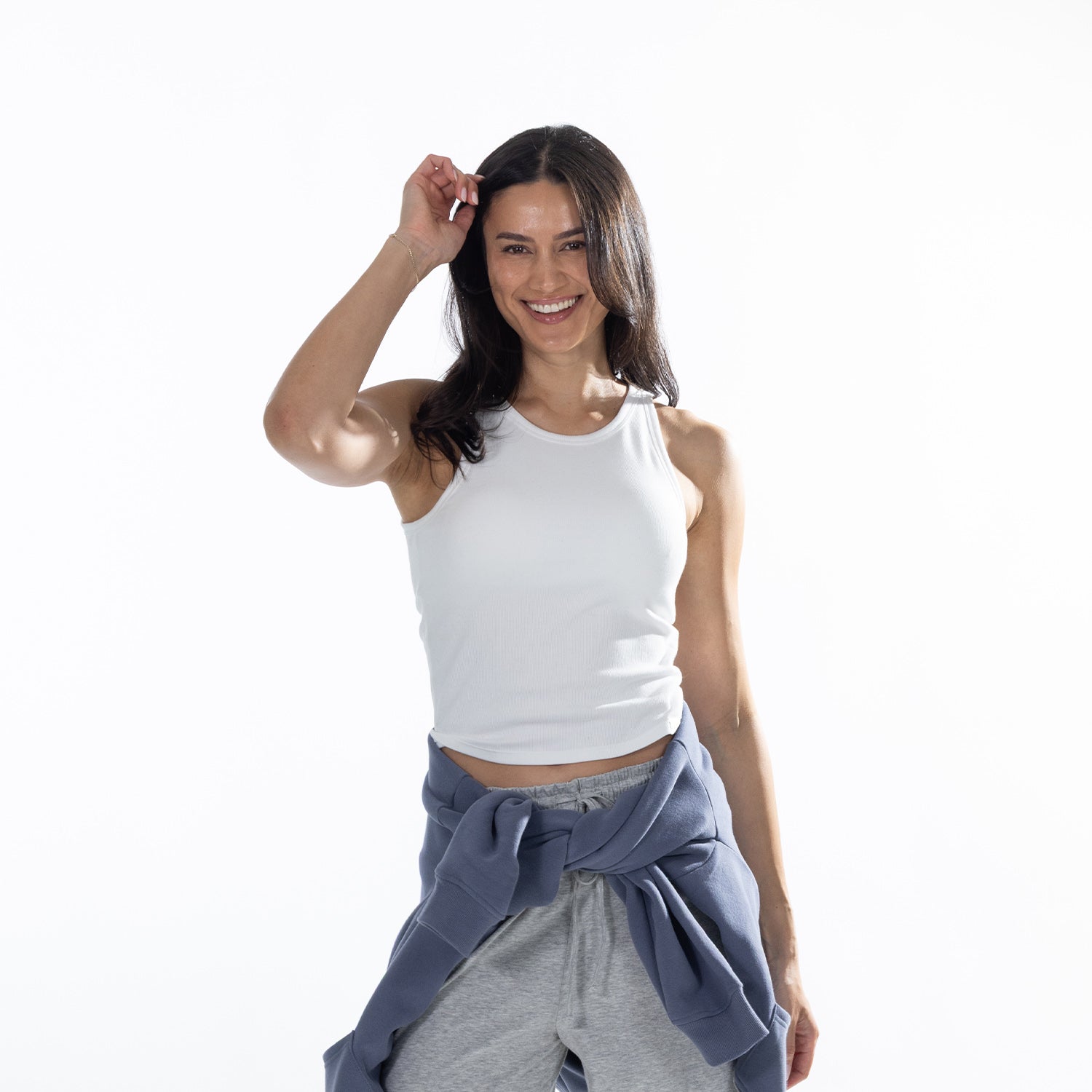 Model wearing the White Simple & Sunday Lounge Weekend Ribbed Tank Top with grey wide-leg lounge pants and a blue sweatshirt tied around the waist.
