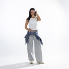 Model wearing the Simple & Sunday Lounge Weekend Ribbed Tank Top in White with grey wide-leg lounge pants, white sneakers and a blue sweatshirt tied around the waist.
