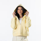 Model wearing a banana embroidered zip hoodie with the hood up over a white tank top and striped shorts.