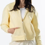A person wearing a pale yellow zip-up hoodie with large outlined 'S&S' lettering across the chest, shown against a plain light background.