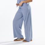 Close-up of the model wearing faded blue striped lounge pants, highlighting the drawstring waistband and wide-leg fit.