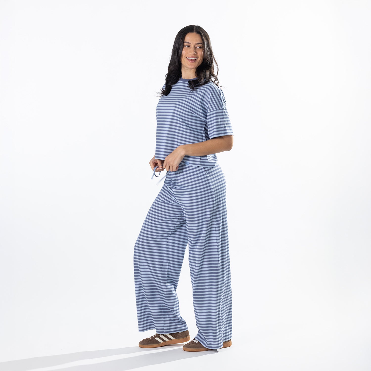 Model wearing faded blue striped lounge pants with a matching striped tee in a side pose.