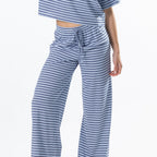 Close-up of the model wearing faded blue striped lounge pants with a matching striped tee, showing the drawstring waistband and stripe detail.