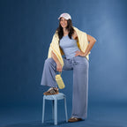 Model wearing faded blue striped lounge pants with a blue ribbed tank top and yellow zip hoodie draped over the shoulders.