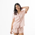 Woman modelling the pink printed satin pyjama set with a short-sleeve button-up top, revere collar and matching shorts.