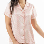 Close-up of the pink pyjama top, highlighting the button front, revere collar, short sleeves and repeating boho-inspired print.