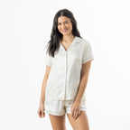 Woman modelling the ivory floral satin pyjama set with a short-sleeve button-up top and matching shorts.