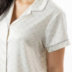 Close-up of the ivory pyjama top, highlighting the delicate floral print, revere collar and contrast piping.