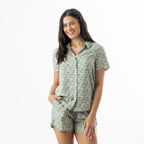 Woman modelling a sage floral print pyjama set with a short sleeve button-up shirt and matching shorts.