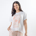 A relaxed-fit white sleep tee features a soft blush floral graphic with elegant typography, creating a fresh and feminine look perfect for comfortable lounging and bedtime.