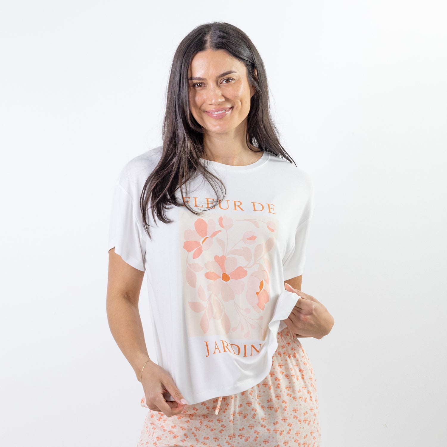 A relaxed-fit white sleep tee features a soft blush floral graphic with elegant typography, creating a fresh and feminine look perfect for comfortable lounging and bedtime.