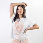 A relaxed-fit white sleep tee features a soft blush floral graphic with elegant typography, creating a fresh and feminine look perfect for comfortable lounging and bedtime.