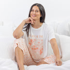 A relaxed-fit white sleep tee features a soft blush floral graphic with elegant typography, creating a fresh and feminine look perfect for comfortable lounging and bedtime.