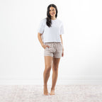 A woman modeling a white short-sleeve cropped t-shirt and natural-and-white gingham drawstring shorts against a plain white background.