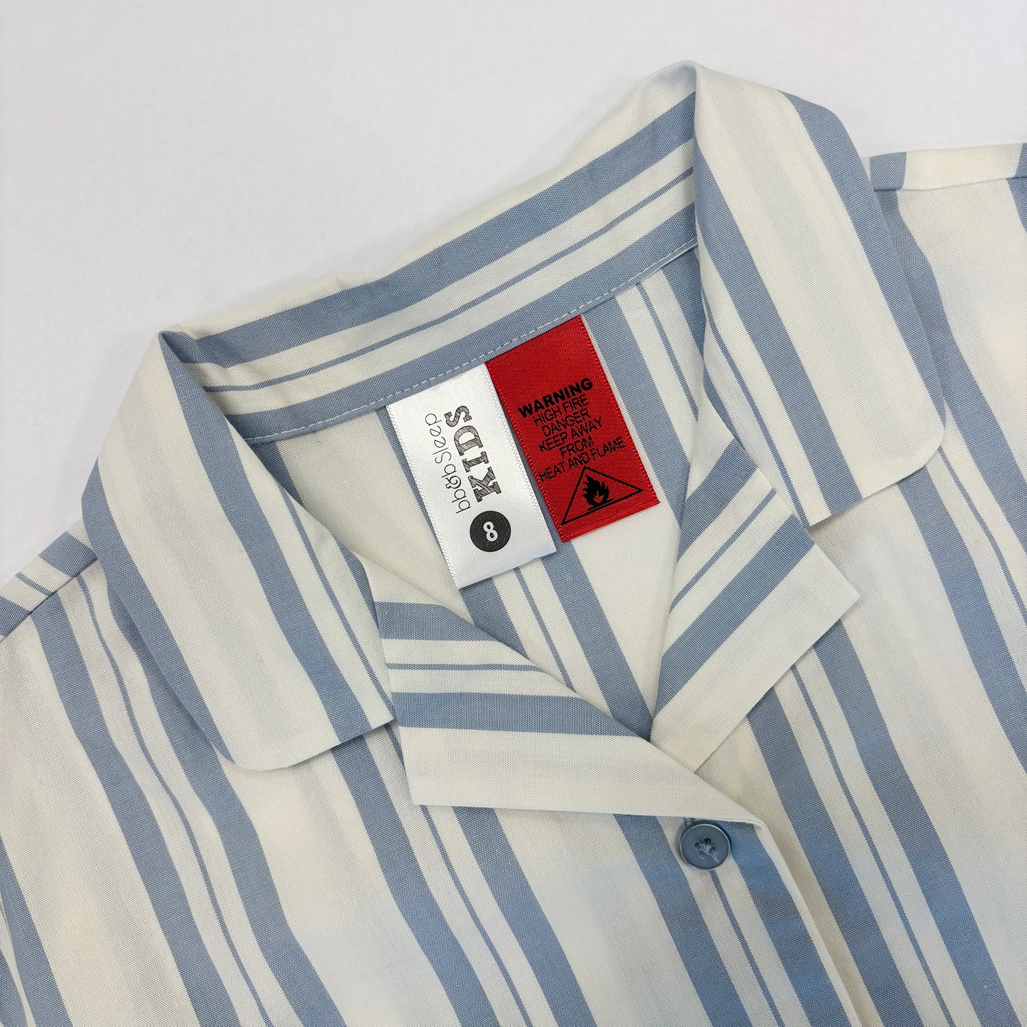 Close-up of a striped kids' collared shirt with a white and light blue pattern, showing the inner neck labels.