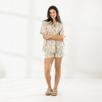 Model wearing the Cove Breeze Shirt with matching printed shorts while holding a bouquet of white flowers and a baguette.