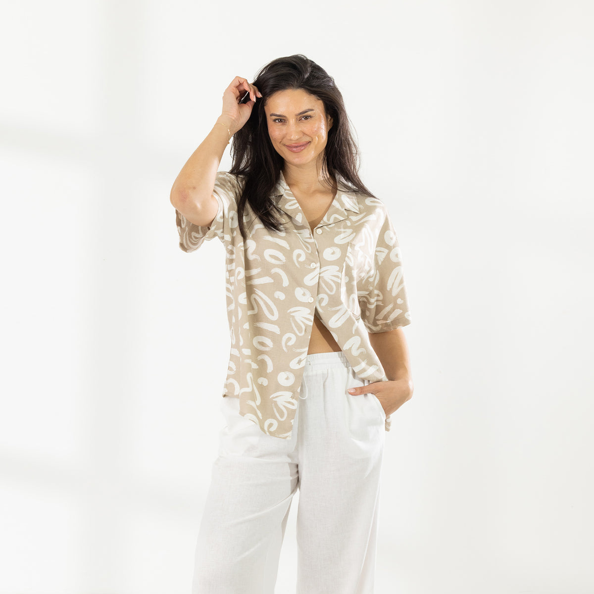 Model wearing the Cove Breeze Shirt in Natural with white relaxed-fit pants against a white studio background.