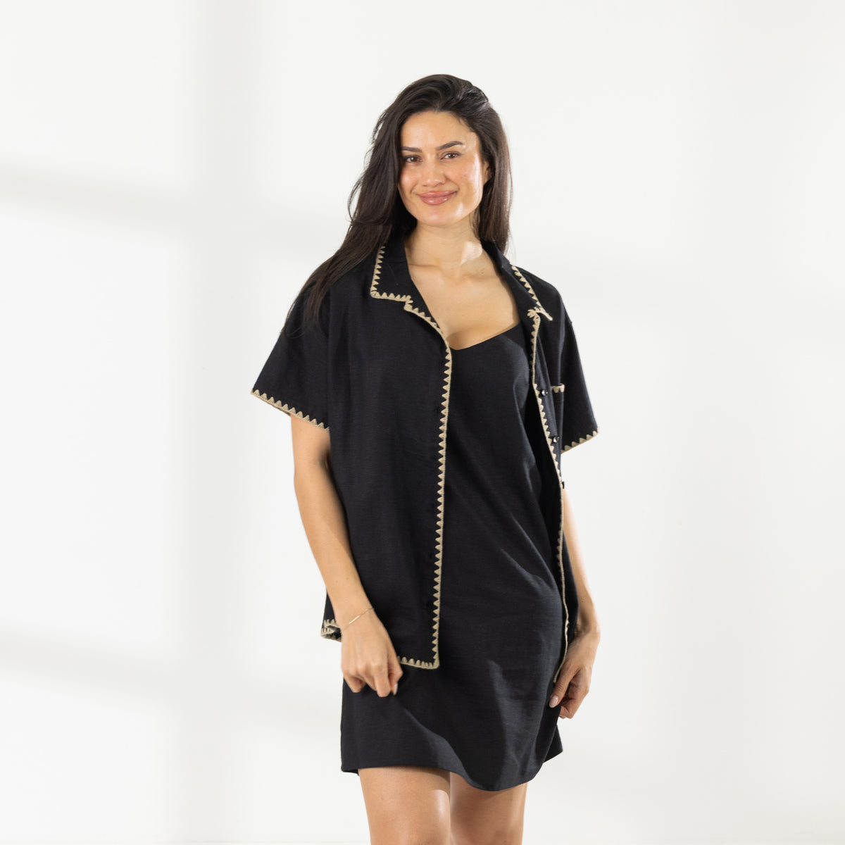 Model wearing the Cove Breeze Stitch Shirt in Black open over a black slip dress, showing the contrast stitch detailing.