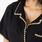 Close-up of the Cove Breeze Stitch Shirt in Black showing the collar, button front and contrast stitch detailing.