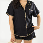 Model wearing the Cove Breeze Stitch Shirt in Black with matching shorts, showing the button front, chest pocket and contrast stitch detailing.