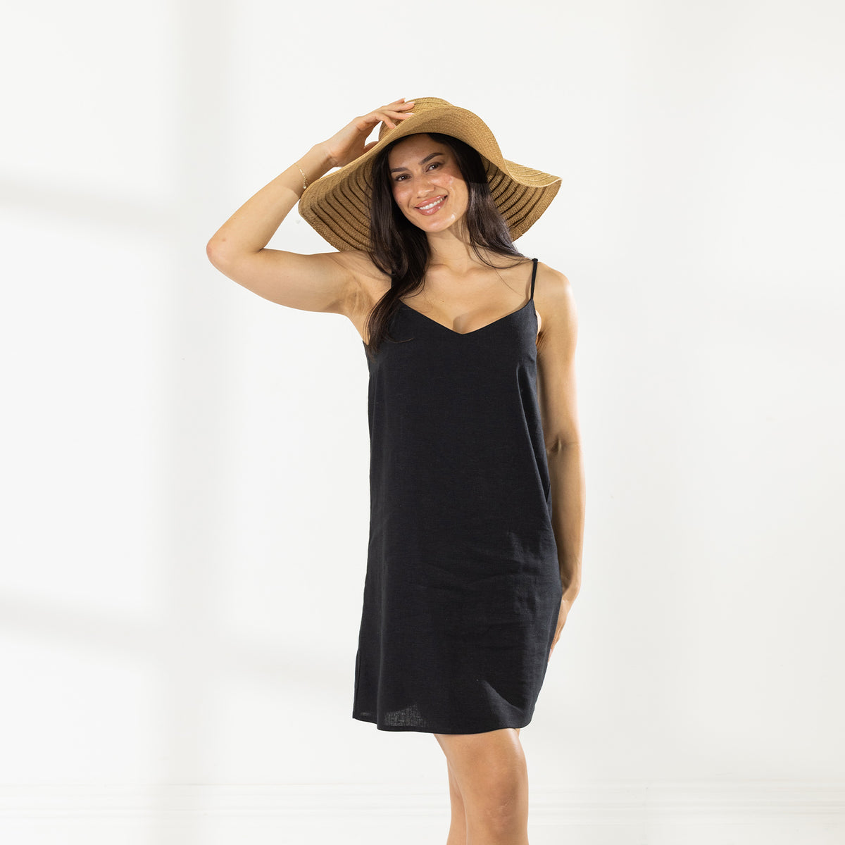 Model wearing the Cove Stitch Slip Dress in Black with a wide-brim straw hat.