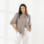 Front view of the model wearing the Cove Breeze Collarless Shirt in Chocolate Check with ivory pants, showing the button front and three-quarter sleeves.