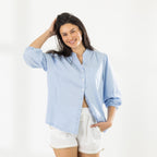 Model wearing the Cove Breeze Collarless Shirt in Chambray with ivory shorts, showing the relaxed fit, button front and three-quarter sleeves.