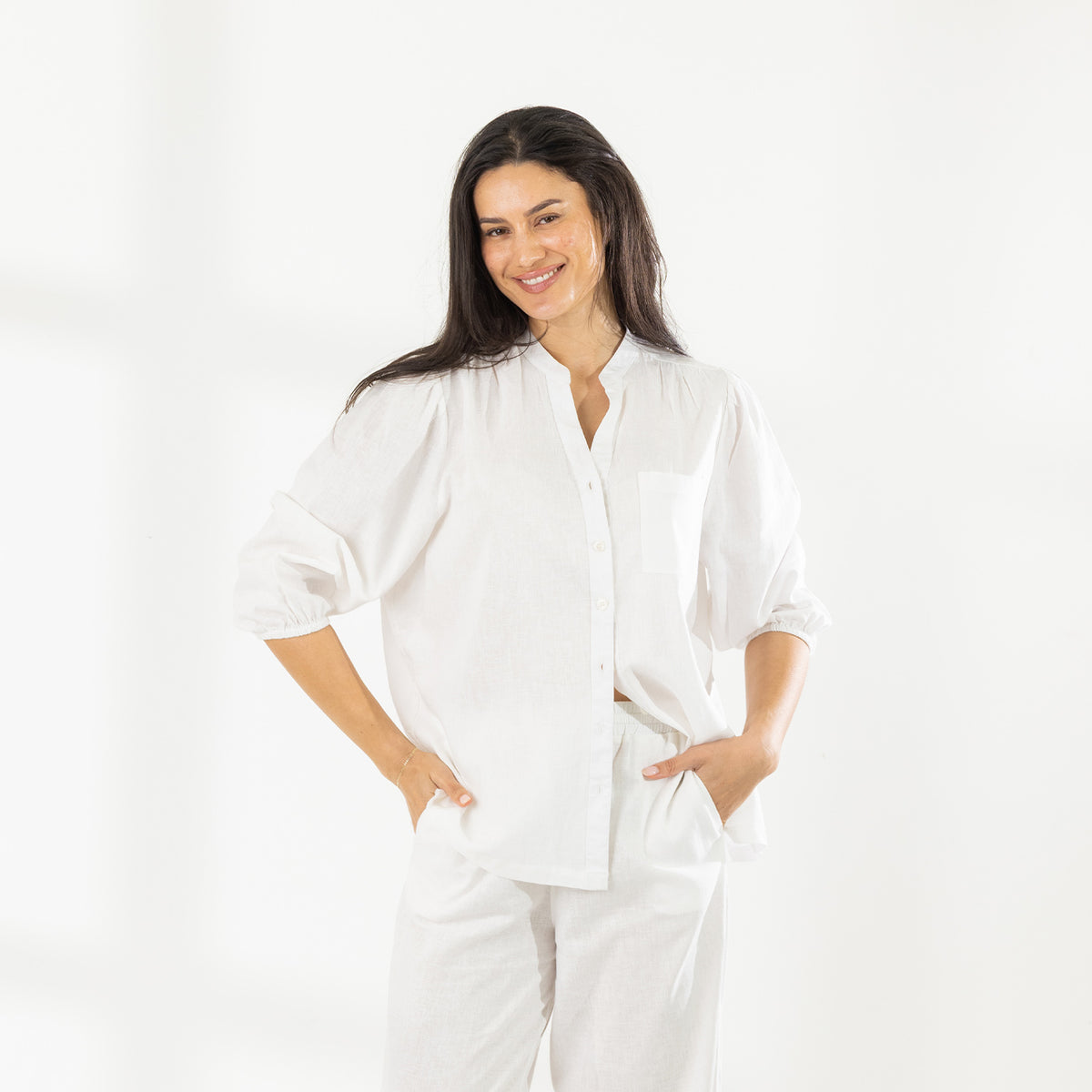 Front view of the model wearing the Cove Breeze Collarless Shirt in Ivory with coordinating ivory pants, showing the button front, chest pocket and three-quarter sleeves.