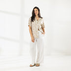 Full-length view of the Cove Breeze Wide Leg Pants in Ivory, styled with a printed short-sleeve shirt and sandals.