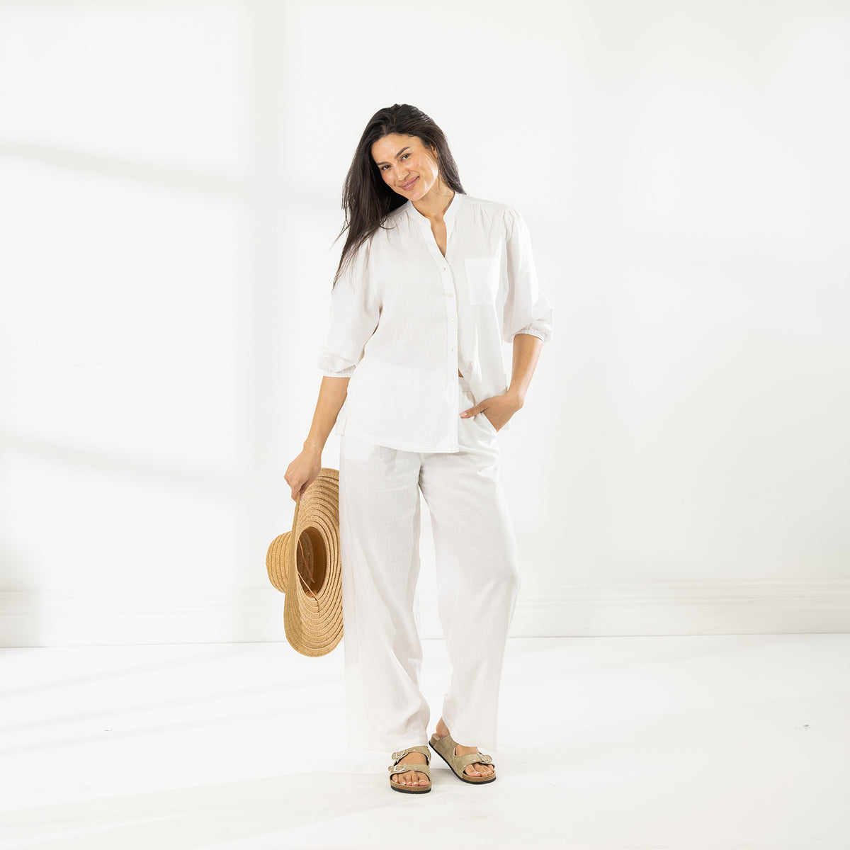 Full-length view of the Cove Breeze Wide Leg Pants in Ivory, styled with a white button-front shirt and sandals.