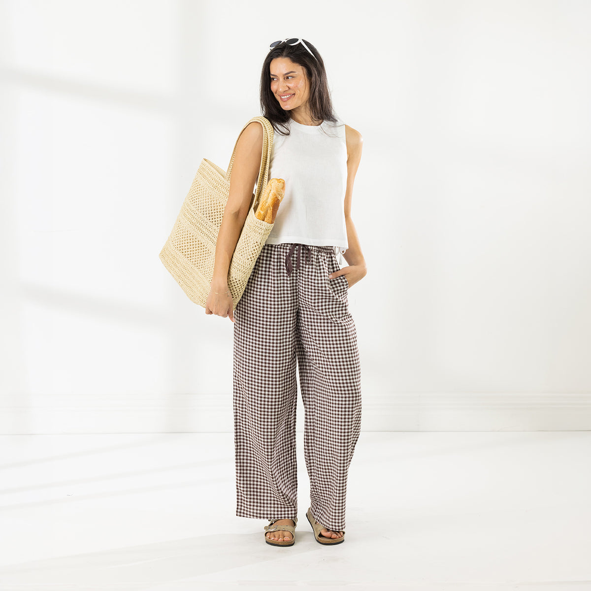 Full-length view of the model wearing the Cove Wide Leg Pants in Chocolate, featuring an all-over gingham check pattern and relaxed wide-leg fit.