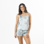 Woman modelling a pale blue satin floral cami pyjama set with blue rose print, featuring a strappy camisole top and matching shorts.