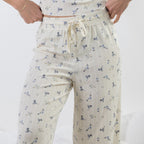 A person wearing cream-colored pj pants with a small blue and yellow floral print, featuring an elastic waistband and drawstring.