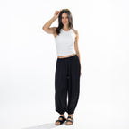 Full-length view of a model wearing black Simple & Sunday Lounge Satin Pants styled with a white sleeveless top and black sandals.
