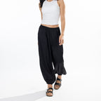 Model wearing black Simple & Sunday Lounge Satin Pants with a relaxed wide-leg fit, elasticated waistband and gathered ankle cuffs.