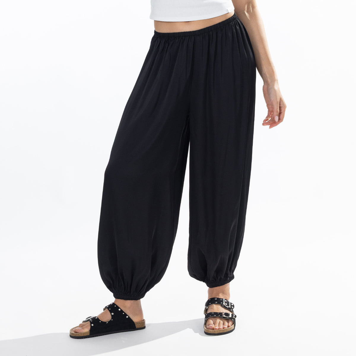 Close-up of black Simple & Sunday Lounge Satin Pants featuring flowing wide legs, an elasticated waistband and gathered ankle cuffs.