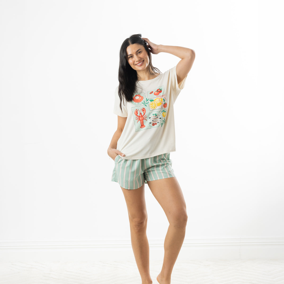 Model posing in an off-white bb&b Sleep Lobster Print Sleep Tee with mint green striped pyjama shorts against a white background.