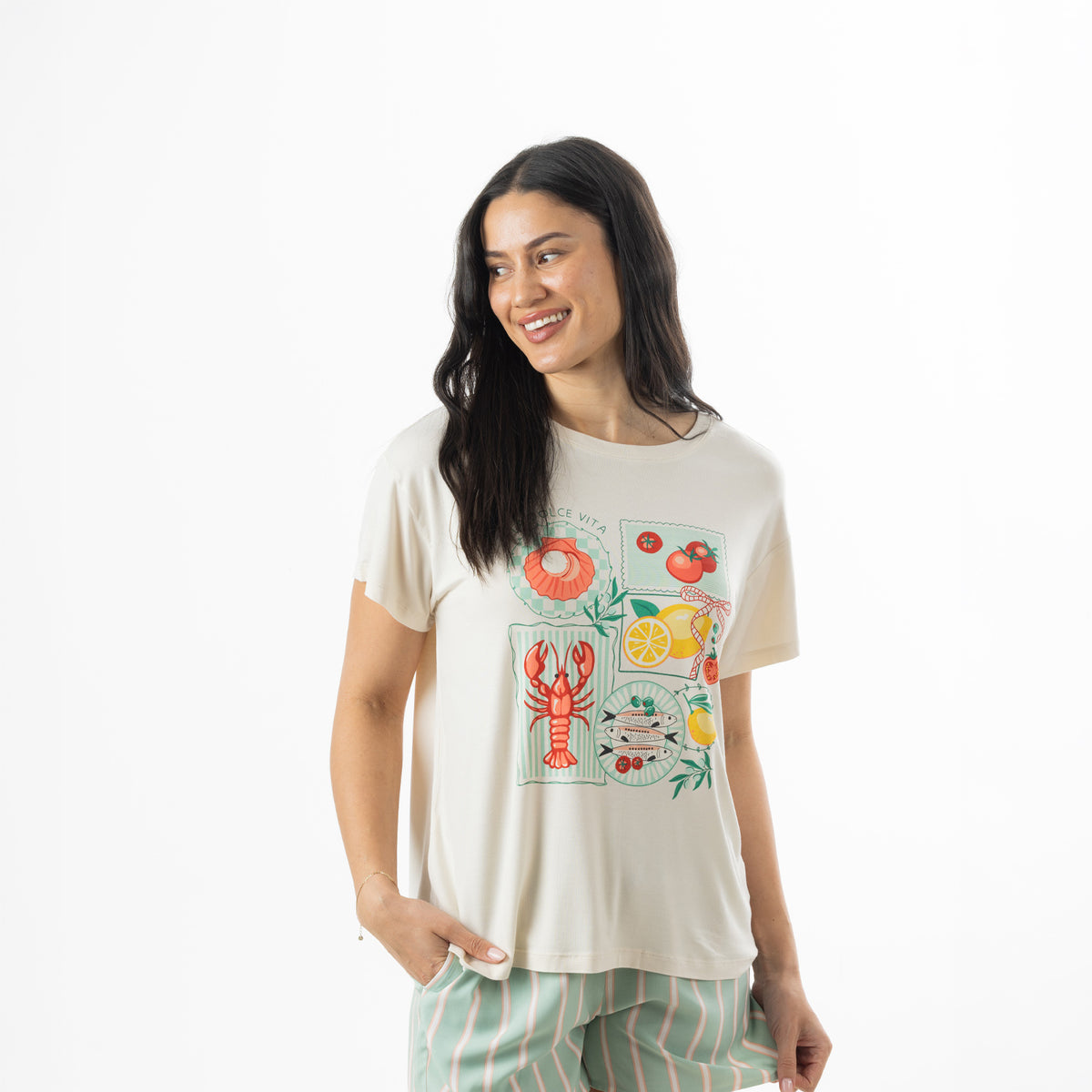 Model wearing an off-white bb&b Sleep Lobster Print Sleep Tee featuring colourful seafood and citrus illustrations, paired with mint green striped pyjama shorts.