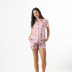 Model wearing the bb&b Sleep XOXO PJ Set in Pink, featuring a short-sleeve button-up shirt and matching shorts with a red heart and cherry print.