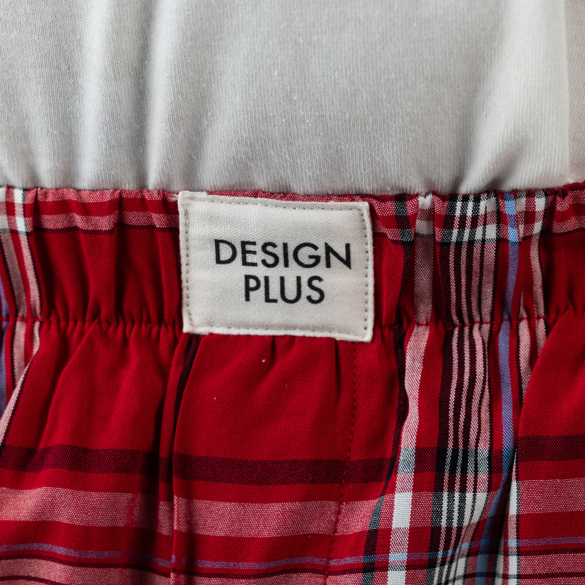 Close-up of the Design Plus Men’s Check PJ Set Red, showing the Design Plus label and red tartan check fabric.