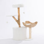 Rear view of the cream cat tower showing the plush hideaway, woven basket bed, elevated perch, natural wood-look scratching post, and dangling pom-pom toys.