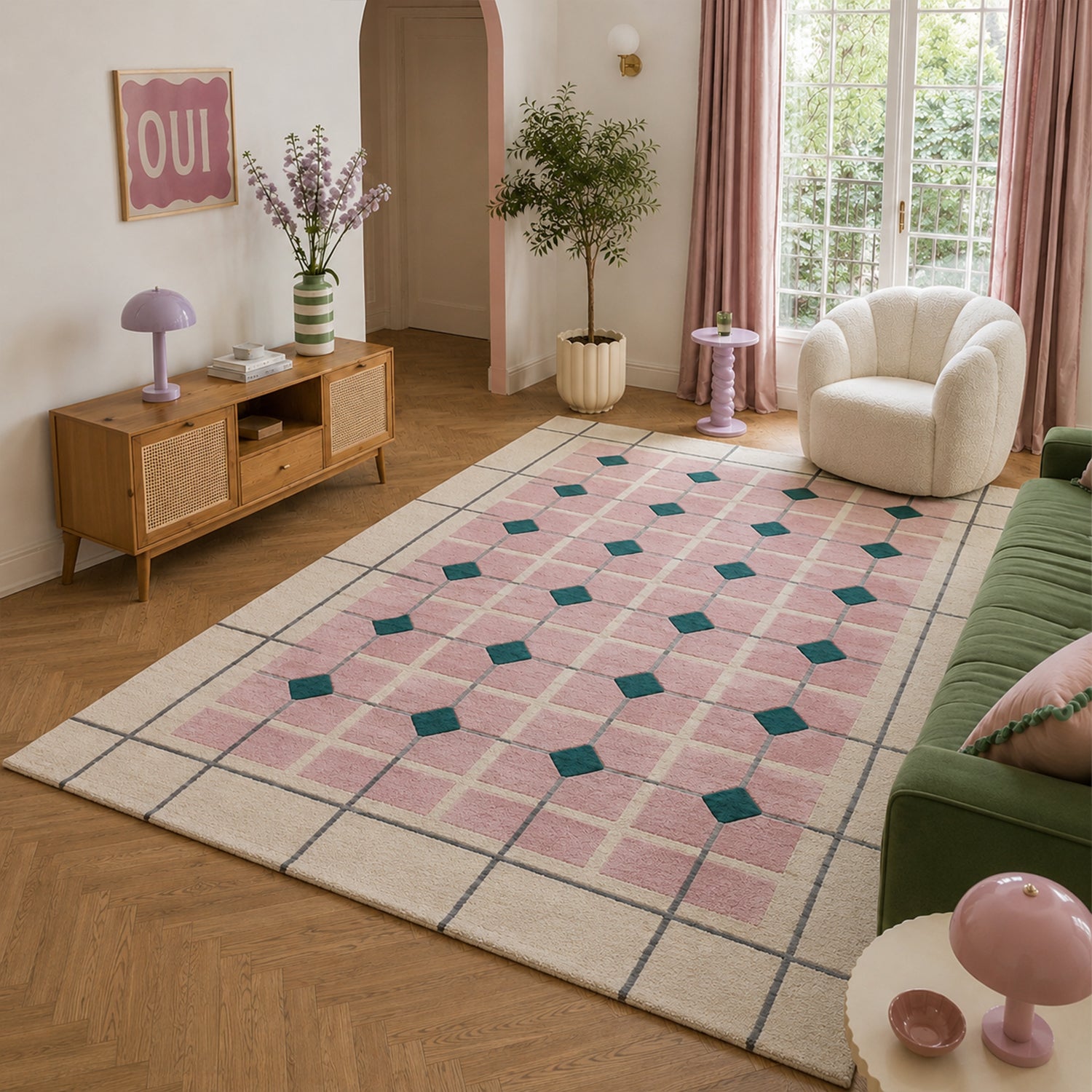 Large pink geometric wool and viscose area rug styled in a bright living room with a green sofa, white accent chair, timber sideboard and blush décor.