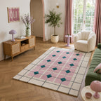 Pink geometric wool and viscose area rug styled in a bright living room with a green sofa, white accent chair, timber sideboard and blush décor.