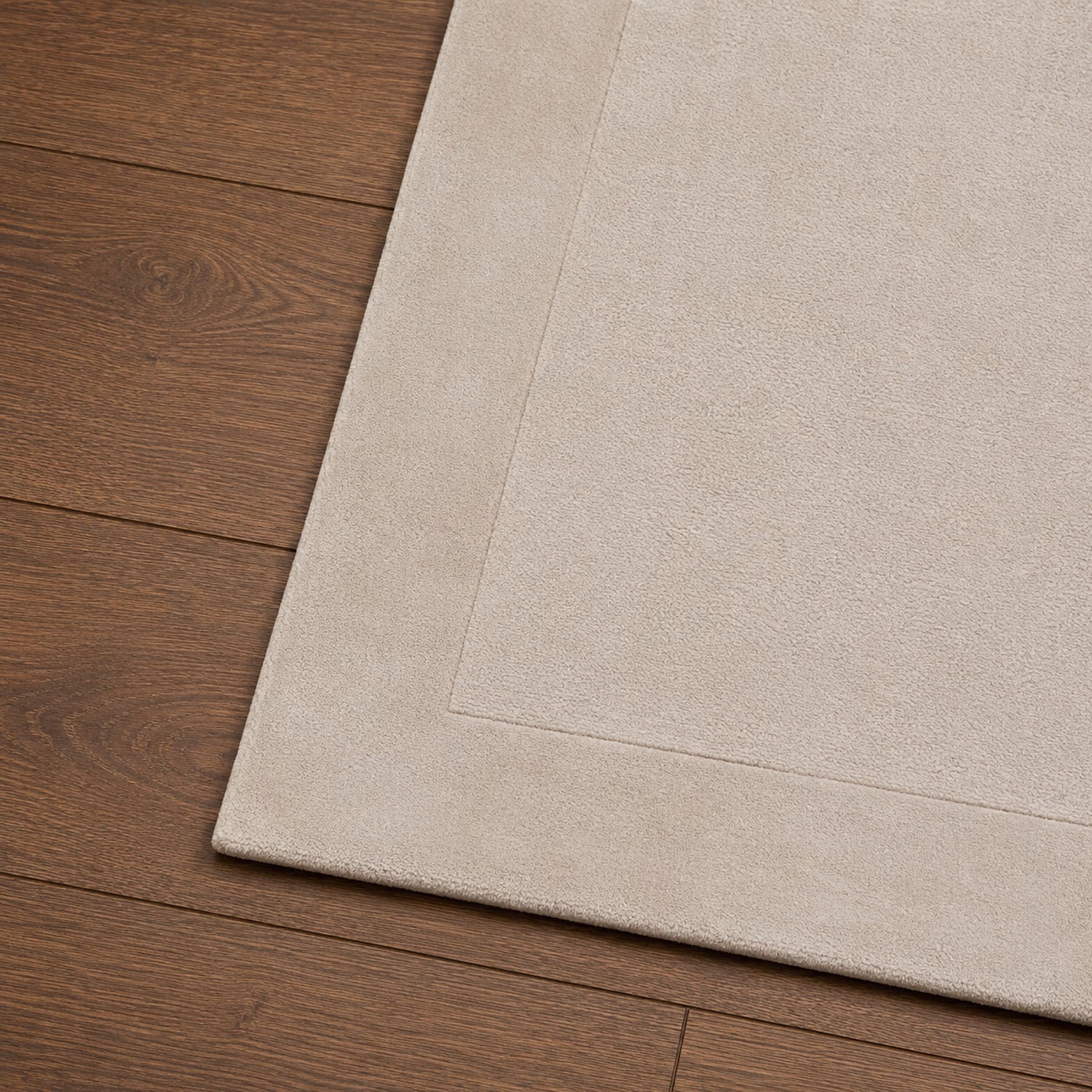 Close-up of the Gracious Living Sabrina Ivory Area Rug showing the soft textured pile, stitched border detail and rounded corner on warm timber flooring.