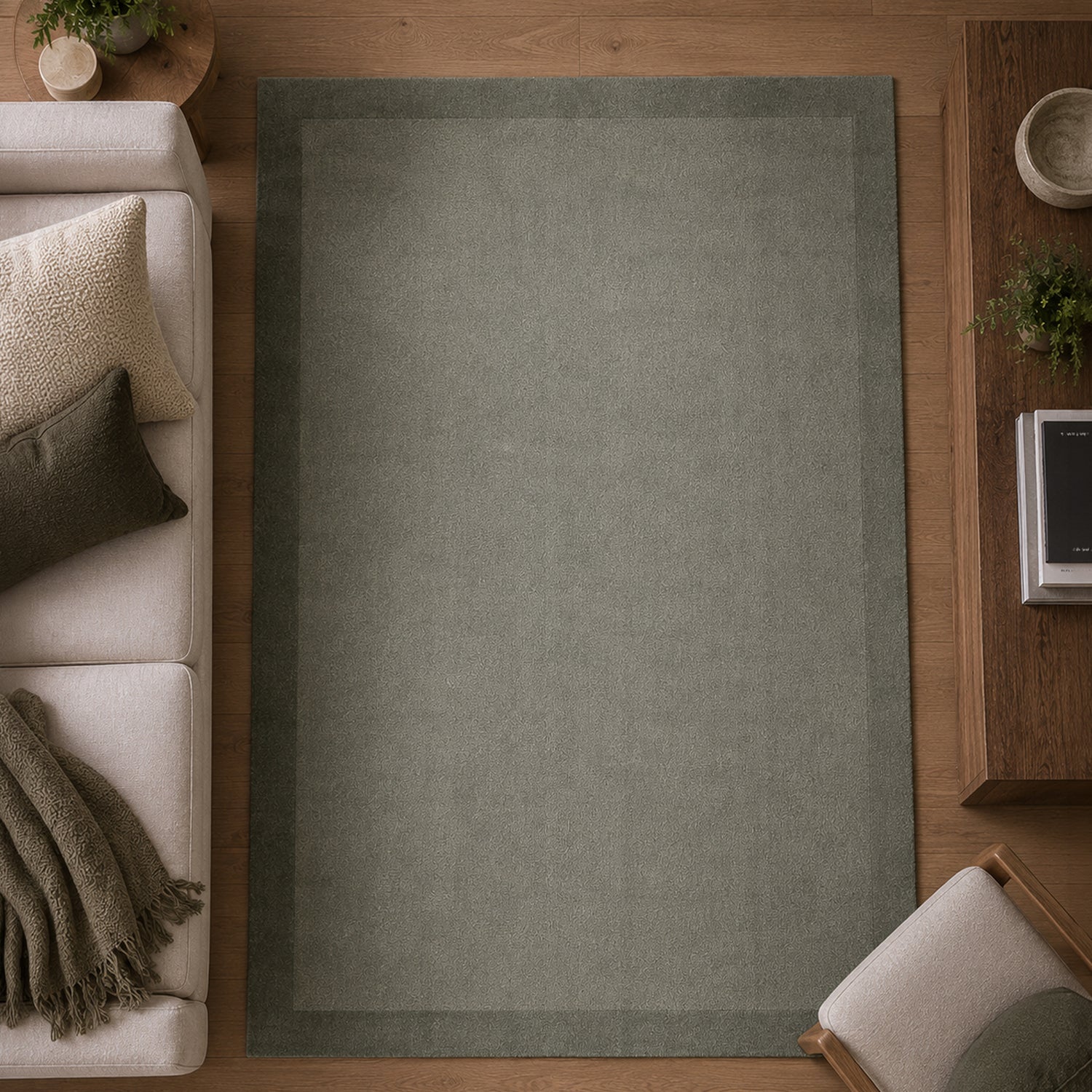 Gracious Living Sabrina Sage Area Rug with a soft plain design and subtle border detail, styled in a contemporary living room with warm timber flooring, a cream sofa and wooden furniture.